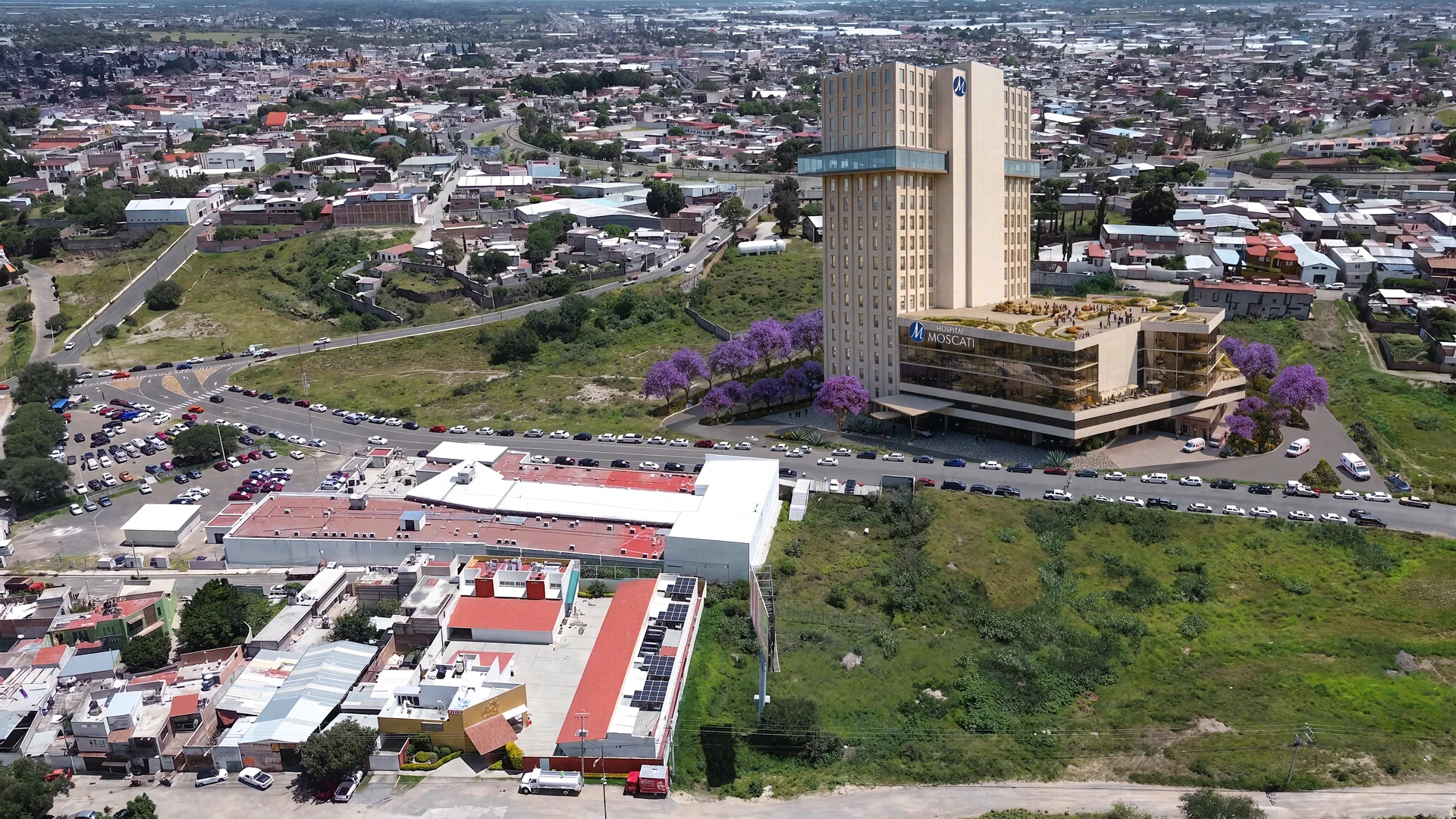 El hospital urbanizado, de día, con la ciudad alrededor